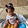 toddler, child, baby, outdoor, bubbles, toy, ring_toy, blanket, hair_bows, curly_hair, white_shirt, rainbow_graphic, sunlight, concrete, playtime, sitting, cute, curious, daylight, fun