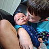 Korbyn joined the competition — help win amazing prizes! adult, affection, baby, blue_shirt, brown_hair, chair, child, close_up, cuddle, door, family, gray_pants, indoor, infant, kiss, onesie, parent, portrait, seated, smiling