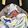 newborn, baby, sleeping, blanket, hood, car_seat, pacifier, infant, cozy, child, soft, cute, rest, baby_clothing, dinosaur_pattern, safety, warning_label, seatbelt, portrait, indoor