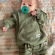 Waylon joined the competition — help win amazing prizes! baby, infant, pacifier, green_clothing, socks, blanket, floral_pattern, lying_down, cute, child, cozy, indoors, portrait, young_child, person, small_hands, small_feet, casual_wear, resting, soft_lighting