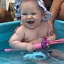 baby, child, water, pool, toy, hat, dinosaur_print, smile, splash, playful, hands_supporting, outdoor, summer, fun, person, skin, animal_tail, pet, purple_toy, blue_pool