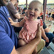 Miller is registered to the contest to win money with this photo: baby, adult, smile, outdoor, crowd, sunset, person, clothing, holding, event, spectator, seat, bench, happy, face, people, casual, daylight, parent, child