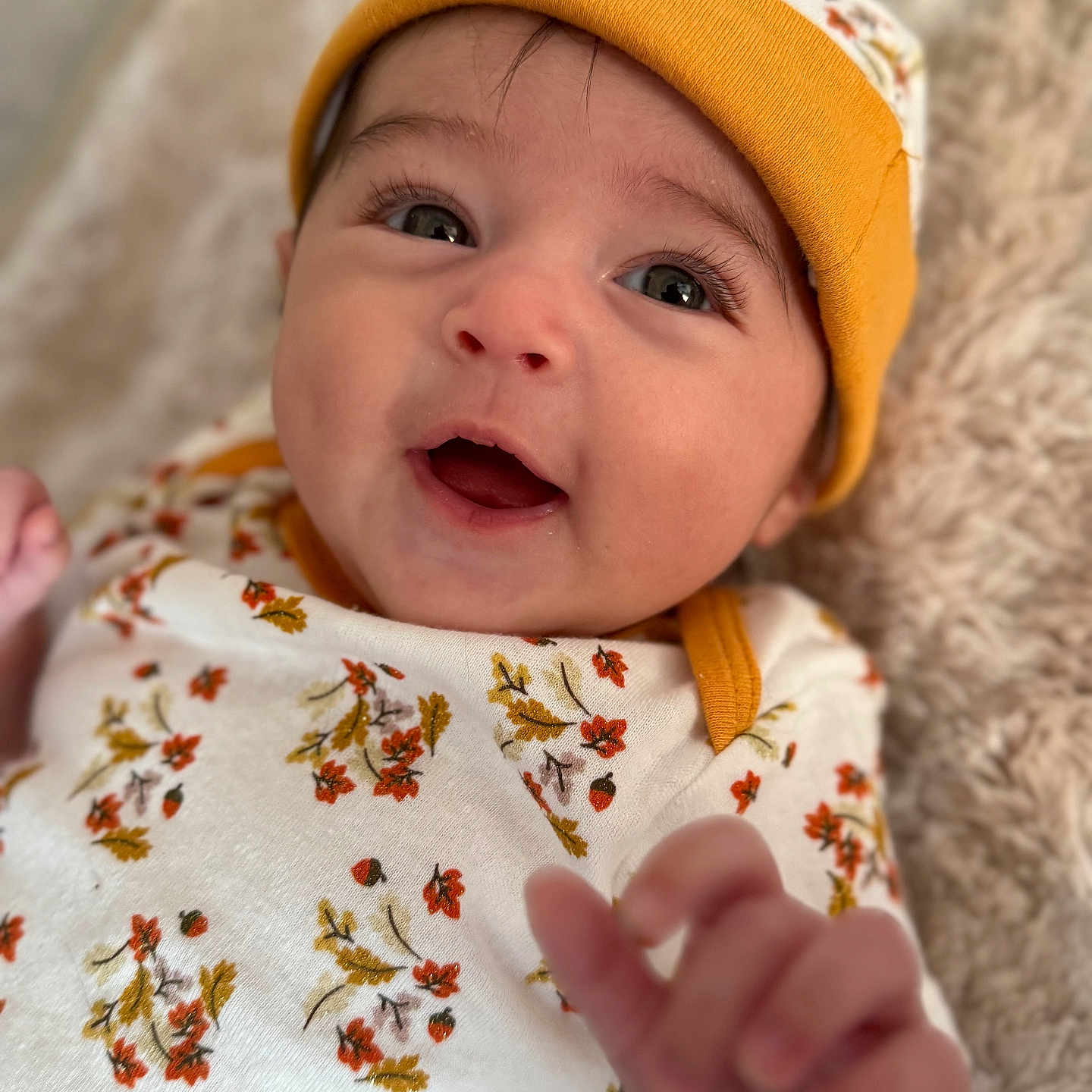 Zaniyah is registered to the contest to win money with this photo: apparel, baby, blanket, child, cozy, cute, expression, eyes, face, floral_clothing, hand, hat, indoors, infant, lying_down, portrait, skin, smiling, soft_texture, young