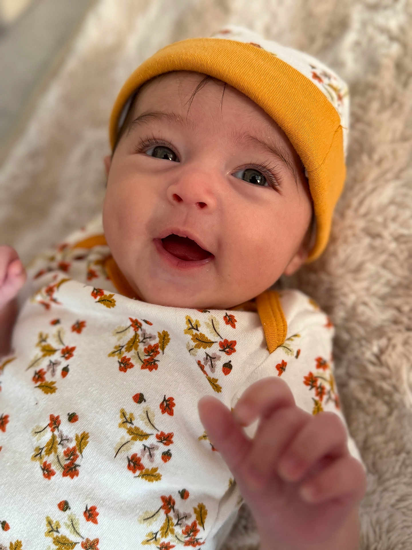Zaniyah is registered to the contest to win money with this photo: baby, infant, smiling, hat, floral_clothing, hand, face, eyes, blanket, cozy, child, cute, portrait, apparel, expression, skin, lying_down, young, soft_texture, indoors