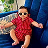 baby, bare_feet, blue_couch, child, cozy, cushion, cute, fashion, houseplant, indoor, infant, living_room, photograph, portrait, red_outfit, relaxed, seated, smiling, striped_clothing, sunglasses