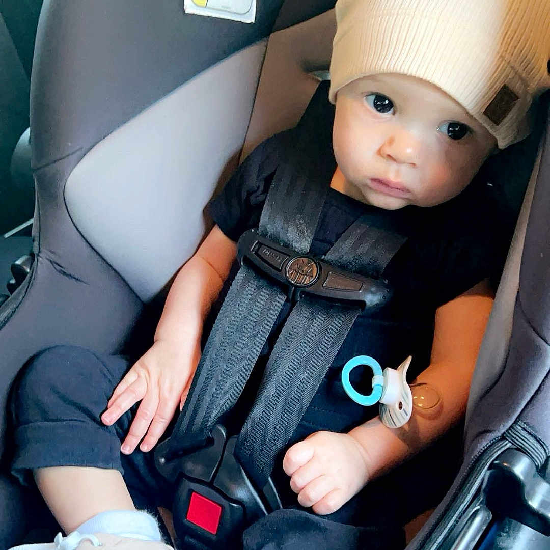 Khyvan is registered to the contest to win money with this photo: accessories, baby, belt, cap, car, car_interior, carseat, clothing, face, footwear, hat, head, pants, person, photography, portrait, shoe, sitting, transportation, vehicle