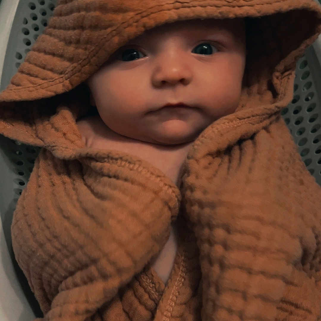 Charlie is registered to the contest to win money with this photo: baby, blanket, bonnet, cap, clothing, coat, face, happy, hat, head, hood, hoodie, knitwear, person, photography, portrait, smile, sunhat, sweater, sweatshirt