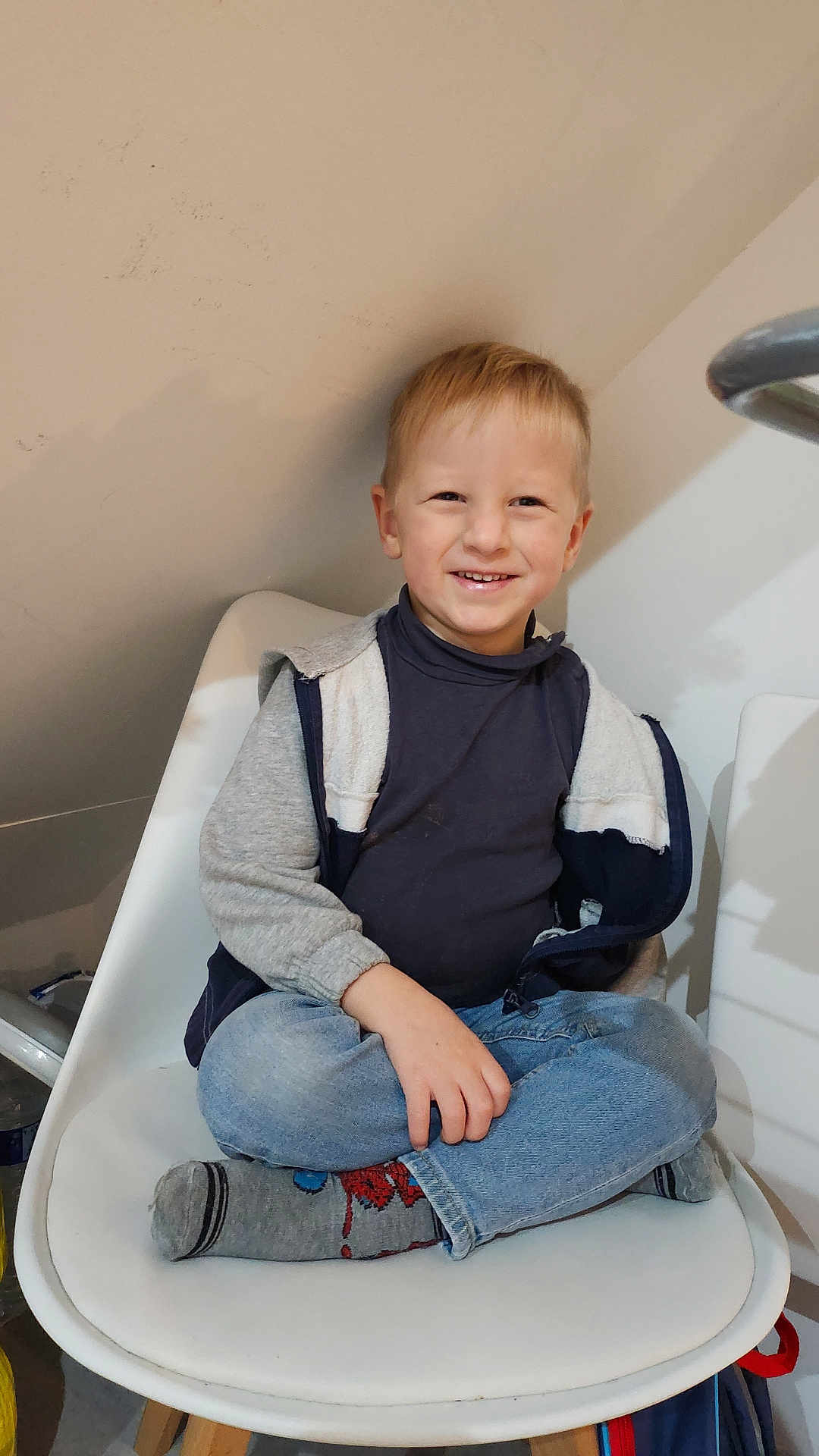 Naël participe au concours pour gagner de l'argent avec cette photo : child, boy, smiling, sitting, chair, indoor, cross_legged, casual_clothing, jeans, socks, blonde_hair, happy, portrait, person, jacket, turtleneck, home, young, cute, relaxed