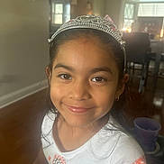 Valentina joined the competition — help win amazing prizes! child, girl, smile, tiara, white_shirt, indoor, portrait, face, long_hair, happy, home, furniture, window, earring, wood_floor, cup, casual_clothing, young, person, natural_light