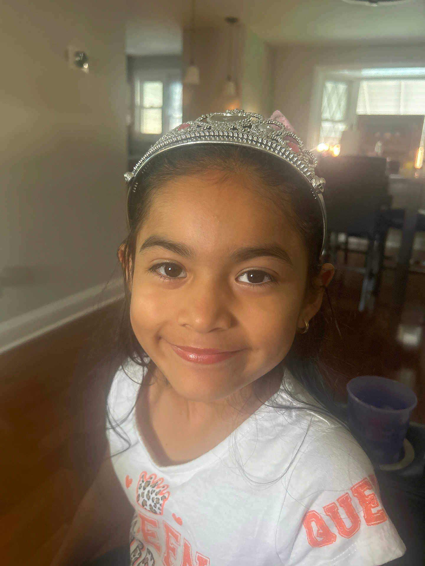 Valentina joined the competition — help win amazing prizes! child, girl, smile, tiara, white_shirt, indoor, portrait, face, long_hair, happy, home, furniture, window, earring, wood_floor, cup, casual_clothing, young, person, natural_light