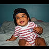 Matheo joined the competition — help win amazing prizes! baby, child, smiling, happy, portrait, bed, bedroom, indoors, baseball_cap, soccer, sportswear, striped_shirt, sitting, infant, face, eyes, teeth, blanket, pillow, photography