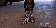 Oakley is registered to the contest to win money with this photo: child, barn, toy_wagon, car, gate, concrete_floor, sunflower_pants, long_sleeve_shirt, smiling, indoor, daylight, rustic, wooden_walls, playful, person, young_child, brown_hair, casual_clothing, open_door, vehicle