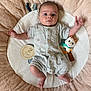 baby, infant, plush_toy, milestone_marker, romper, cushion, soft_texture, lying_down, wide_eyes, baby_clothing, indoor, child, cute, adorable, newborn, two_months, portrait, skin, hand, foot