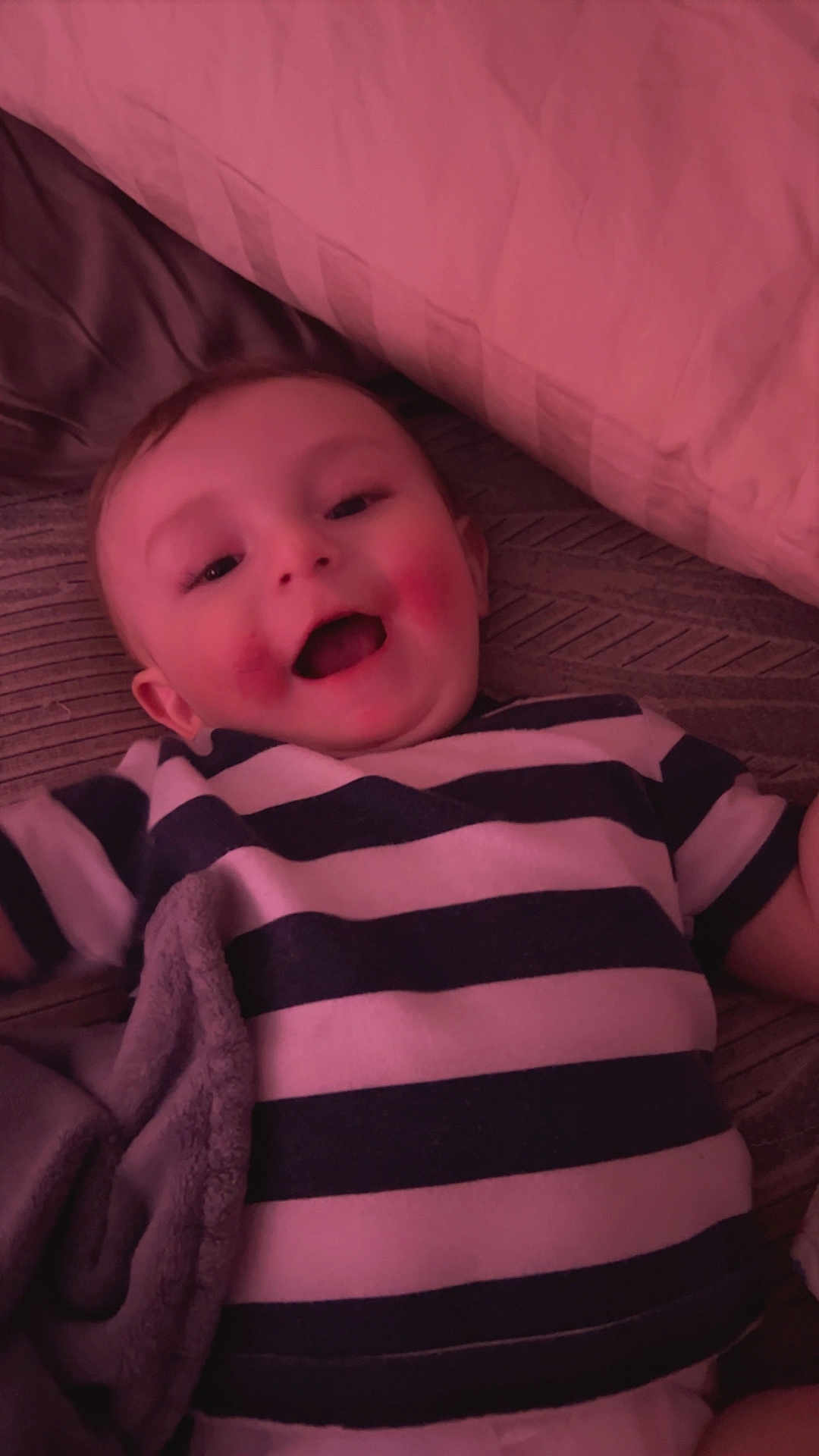 Andrew joined the competition — help win amazing prizes! baby, child, smiling, striped_shirt, lying_down, blanket, cozy, happy, rosy_cheeks, indoor, face, infant, cute, soft_texture, person, portrait, young_child, sleepwear, comfort, toddler