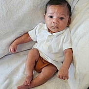 Alijah is registered to the contest to win money with this photo: baby, infant, child, blanket, white, polo_shirt, brown_shorts, face, eyes, expression, sitting, cozy, plush, soft, embroidery, name, cute, small, indoors, portrait