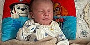 Marcus is registered to the contest to win money with this photo: baby, sleeping, blanket, pillow, paw_patrol, bottle, crib, onesie, mittens, toy, infant, bedtime, cute, resting, child, nursery, comfort, soft, peaceful, home