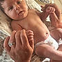Ryker joined the competition — help win amazing prizes! baby, infant, hand, adult_hand, diaper, pillow, patterned_fabric, skin, face, eyes, mouth, naked_torso, holding_hands, bed, curtain, window, light, person, newborn, family