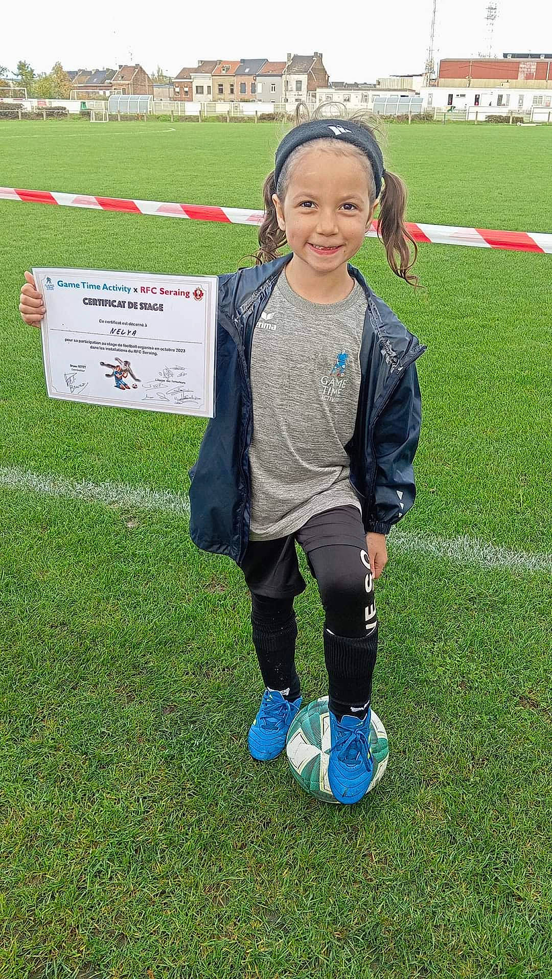 Nélya participe au concours pour gagner de l'argent avec cette photo : ball, competition_event, football, football_player, fun, grass, jacket, joy, leisure, person, player, recreation, shorts, smile, soccer_ball, sports, sports_equipment, sportswear, team_sport, toddler