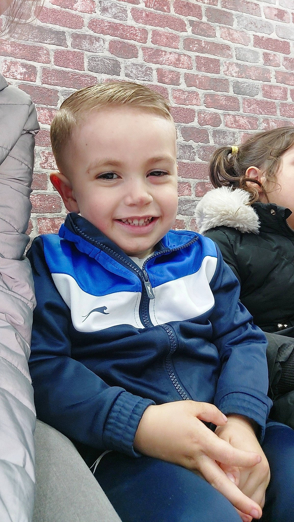 Ninho a rejoint le concours — aidez-le/la à gagner de superbes lots ! cheek, child, electric_blue, event, facial_expression, fun, grass, happy, head, joy, laugh, leisure, person, recreation, sitting, sleeve, smile, toddler, tree, uniform