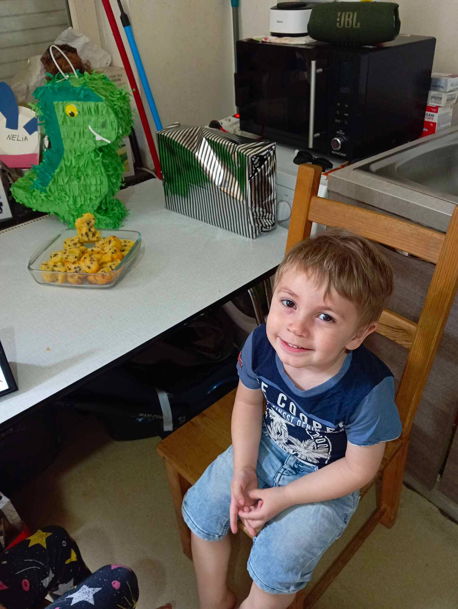 Ninho participe au concours pour gagner de l'argent avec cette photo : chair, child, computer_desk, desk, flooring, fun, green, home_appliance, human_leg, joy, kitchen_appliance, person, room, shorts, sitting, smile, t_shirt, table, thigh, toddler