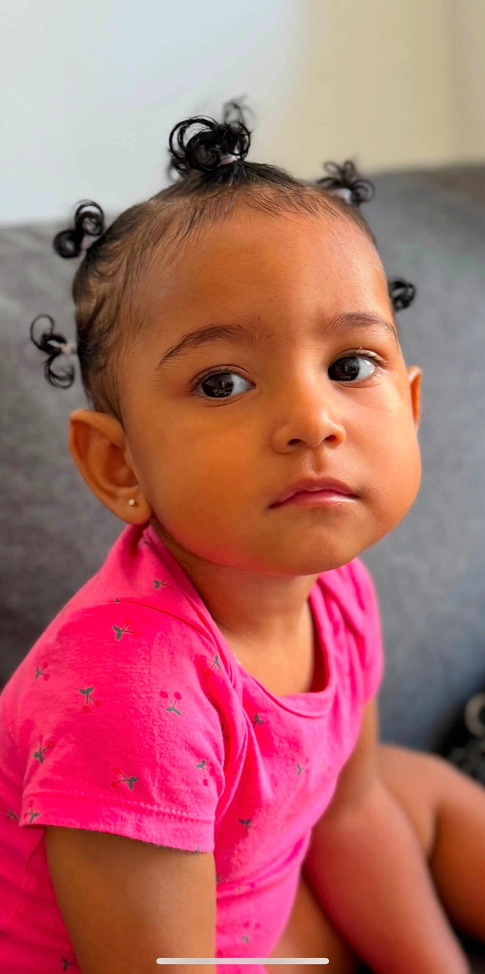 Shayanne a rejoint le concours — aidez-le/la à gagner de superbes lots ! toddler, child, portrait, face, curly_hair, pink_shirt, cherry_pattern, earring, indoor, couch, seated, cute, young_child, expression, skin, person, looking_away, hairstyle, casual_clothing, closeup
