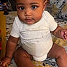 Dallas is registered to the contest to win money with this photo: baby, infant, child, cute, sitting, onesie, socks, bed, bedspread, patterned, curly_hair, indoors, portrait, person, young, looking_at_camera, skin, hand, foot, expression