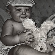 Yacine a rejoint le concours — aidez-le/la à gagner de superbes lots ! baby, child, cap, hat, stuffed_animal, plush_toy, smile, portrait, cushion, indoor, closeup, cute, chubby, happy, infant, holding, soft_toy, monochrome, face, person