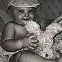 baby, child, cap, hat, stuffed_animal, plush_toy, smile, portrait, cushion, indoor, closeup, cute, chubby, happy, infant, holding, soft_toy, monochrome, face, person