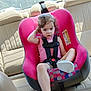 beige, car_interior, car_seat, casual_clothing, child, curly_hair, daylight, footwear, person, pink, portrait, restraint, seat, seatbelt, sitting, sunlight, toddler, vehicle, window, young_child