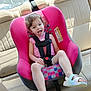 Freyja is registered to the contest to win money with this photo: car_interior, car_seat, casual_clothing, child, curly_hair, cute, leather_seat, pink, playful, safety_harness, sandals, seatbelt, smiling, summer, sunlight, toddler, tongue_out, transportation, vehicle, young