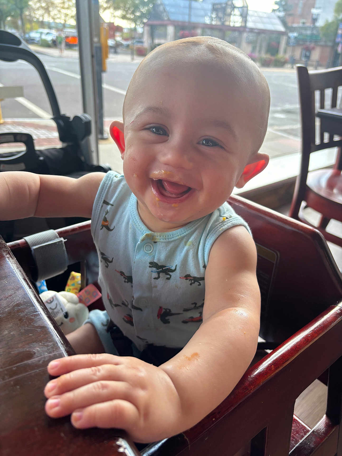 Cassian joined the competition — help win amazing prizes! baby, high_chair, smiling, messy_face, indoor, restaurant, table, arm, clothing, person, child, happy, seat, window, street, toy, wood, daylight, face, expression