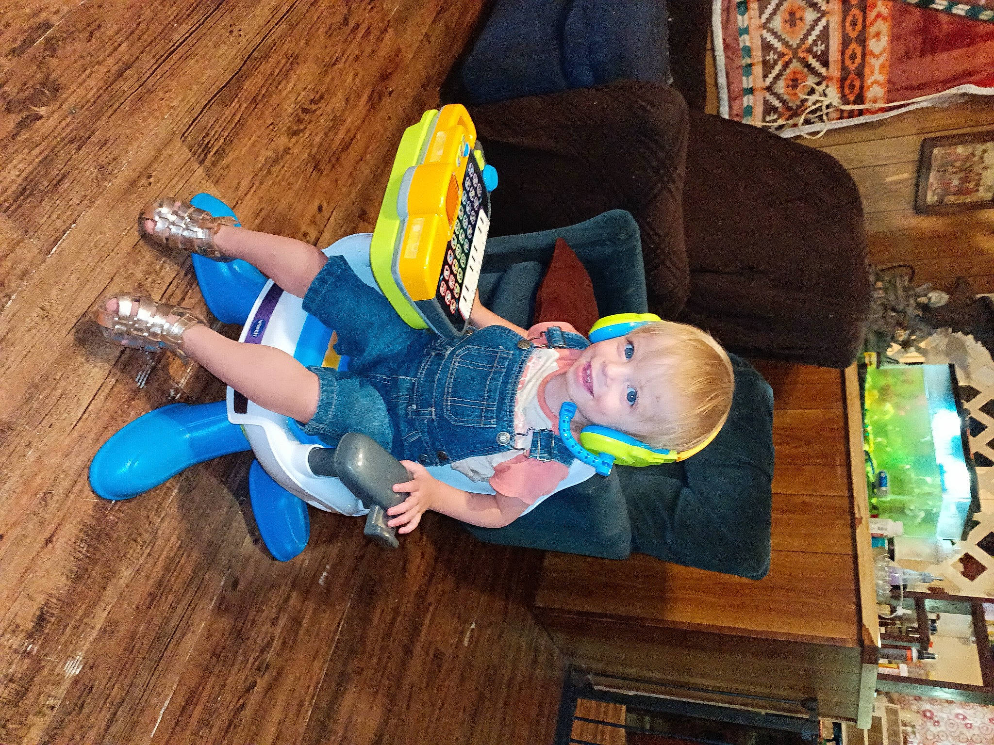 Leanna is registered to the contest to win money with this photo: child, comfort, couch, electric_blue, event, flooring, fun, hardwood, hat, joy, laminate_flooring, leisure, person, picture_frame, room, sitting, toddler, wood, wood_flooring, wood_stain