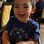 toddler, child, smiling, happy, high_chair, restaurant, indoor, wooden_furniture, blue_tshirt, short_hair, person, table, adult, woman, chair, window, casual_clothing, face, hands, daylight