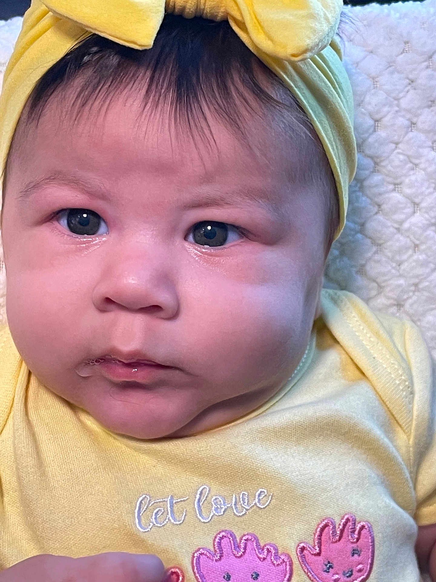 Astrid álvarez joined the competition — help win amazing prizes! baby, close_up, face, yellow_headband, yellow_onesie, infant, cute, expression, soft_blanket, pink_handprints, clothing, portrait, child, newborn, headwear, adorable, skin, eyes, mouth, hand