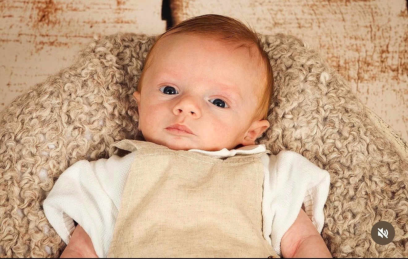 Marceau participe au concours pour gagner de l'argent avec cette photo : baby, infant, blanket, knitted, clothing, beige, white, face, portrait, person, young_child, cute, eyes, head, soft_texture, indoors, resting, cozy, newborn, expression