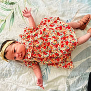 Ambre participe au concours pour gagner de l'argent avec cette photo : baby, infant, child, floral_dress, headband, lying_down, bed_sheet, patterned, footwear, shoes, skin, cute, small_hands, small_feet, indoors, soft_light, portrait, young_child, colorful_clothing, resting