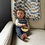 baby, infant, child, armchair, blanket, knit_blanket, plaque, wooden_plaque, three_months, blue_overall, long_sleeve_shirt, animal_print, bare_feet, curious_expression, indoor, cozy, soft_textures, person, portrait, seated