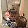 baby, chair, child, curiosity, cute, face, floor, furniture, hair, hand, indoor, mirror, person, pony_tail, radiator, reflection, room, striped_clothing, toddler, wall