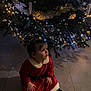 black_tights, celebration, child, christmas, christmas_tree, curious, cute, decorations, festive, festive_clothing, floor, holiday, holiday_season, indoor, lights, portrait, red_dress, sitting, toddler, young_child