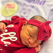 Kianna is registered to the contest to win money with this photo: newborn, baby, sleeping, red_clothing, headband, bow, infant, soft_blanket, closeup, portrait, peaceful, resting, indoors, cute, human, small_hand, face, skin, child, cozy