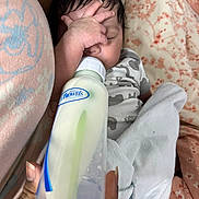 Hermes is registered to the contest to win money with this photo: baby, infant, newborn, sleeping, face, hand, baby_bottle, milk, feeding, onesie, blanket, bedding, closeup, portrait, hair, hand_holding_bottle, patterned_fabric, indoor, cozy, browns_logo