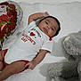 Hermes joined the competition — help win amazing prizes! baby, infant, newborn, onesie, valentine_balloon, heart_balloon, teddy_bear, stuffed_animal, blanket, white_sheet, lying_down, portrait, face, cute, red_text, roses, indoors, clothing, smile, holiday