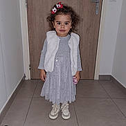 Ambre participe au concours pour gagner de l'argent avec cette photo : child, girl, indoor, door, floor, tile_floor, vest, dress, shoes, bow, curly_hair, pacifier, wall, standing, portrait, cute, fashion, smile, young, person