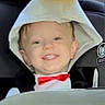 toddler, child, smiling, face, portrait, car_seat, vehicle, indoors, bow_tie, formalwear, hood, towel, yellow, red, happy, seated, car_interior, window, daylight, cute