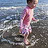 child, toddler, beach, ocean, seaside, water, waves, surf, foam, splashing, outdoors, summer, pink_shirt, shorts, fish_pattern, barefoot, walking, profile, sunlight, portrait
