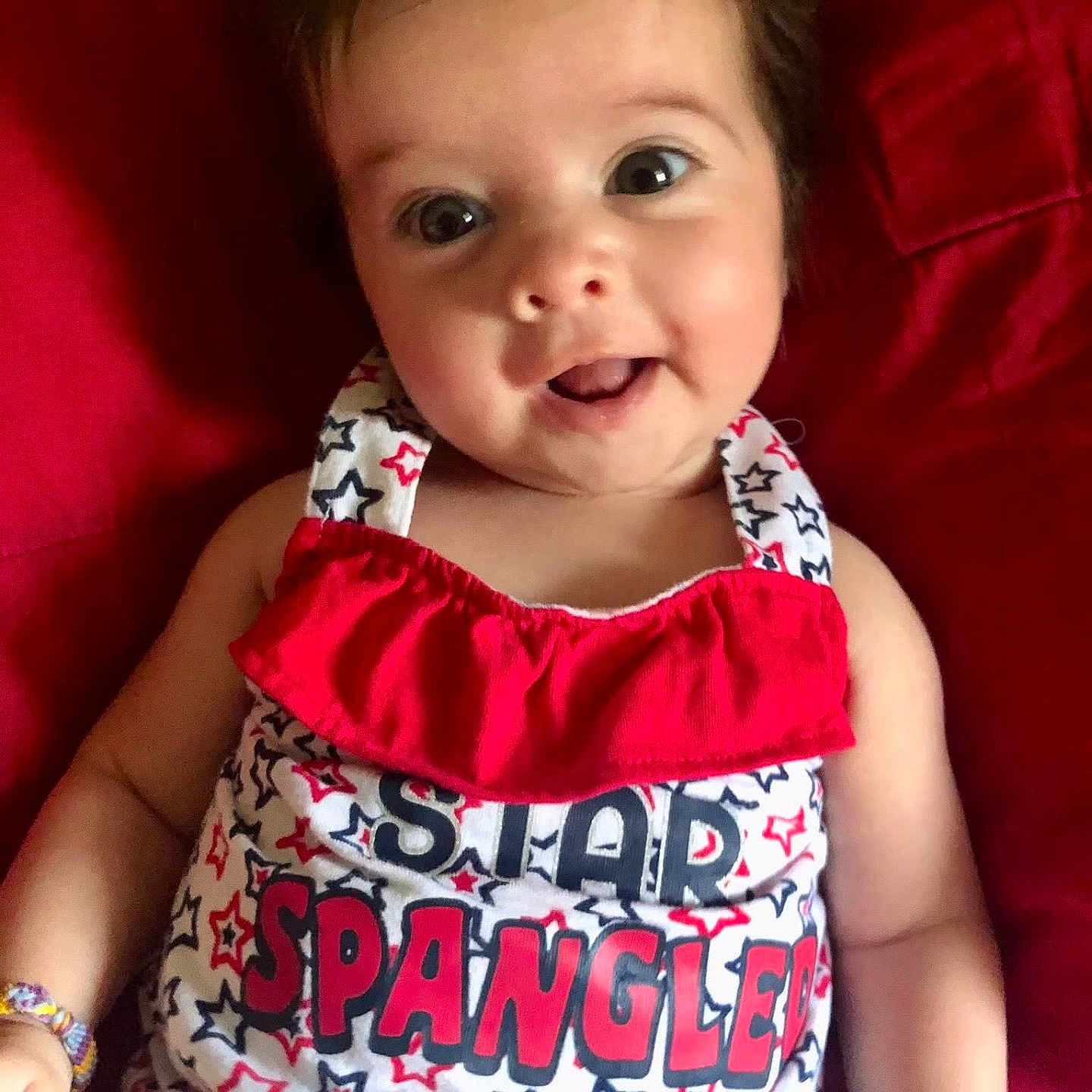 Kaia joined the competition — help win amazing prizes! arms, baby, blue, bracelet, closeup, clothing, cute, eyes, fabric, face, happy, infant, pattern, portrait, red, sitting, smiling, stars, text, white