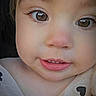 baby, brown_eyes, child, close_up, clothing, curious, cute, eyelashes, eyes, face, head, heart_pattern, outdoor, person, photograph, portrait, rosy_cheeks, skin, smiling, toddler