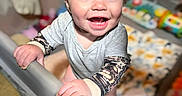Edith is registered to the contest to win money with this photo: baby, child, smiling, playpen, indoor, clothing, tattoo_sleeves, hand, face, happy, toy, blanket, carpet, person, infant, cute, standing, expression, skin, bright_eyes