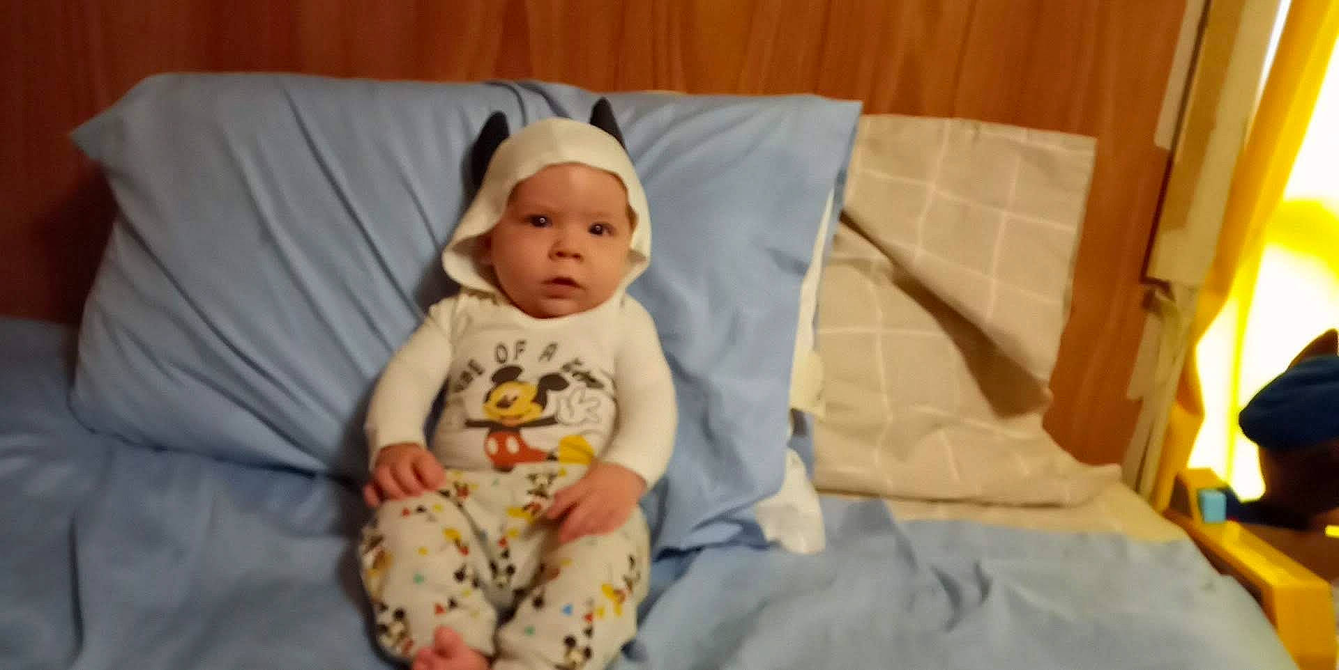 Emery is registered to the contest to win money with this photo: baby, baby_products, baby_safety, baby_toddler_clothing, child, comfort, face, hat, headwear, linens, person, room, sitting, skin, sleeve, smile, t_shirt, toddler