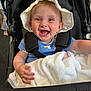 baby, child, stroller, hat, white_hat, blue_shirt, blanket, smile, happy, infant, cute, portrait, indoor, baby_clothes, person, seatbelt, hand, face, joy, expression